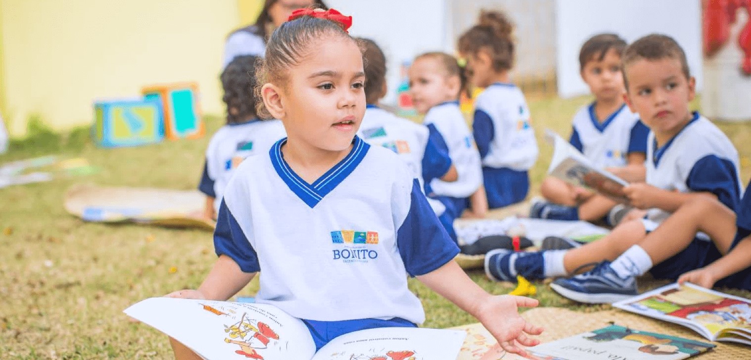 Crianças sentadas ao chão com livros nas mãos. Imagem feita na cidade de Bonito, Pernambuco.