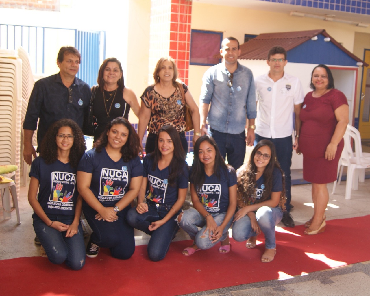 Pessoas posam para a foto - entre elas há adolescentes com uma camisa na qual está escrito NUCA e adultos