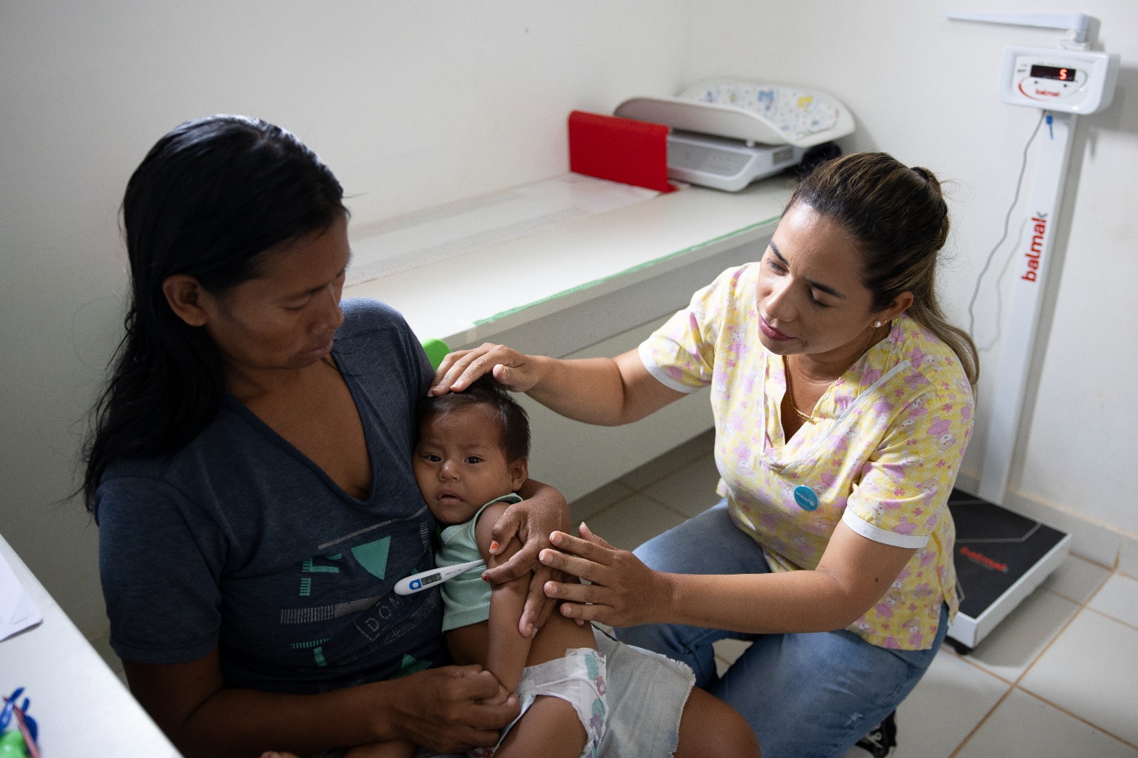 Mãe com bebê indígena sendo atendido por uma profissiona de saúde