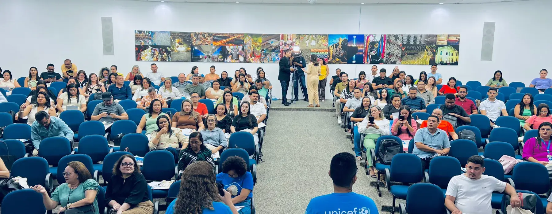 auditorio cheio de pessoas usando camisas azul ciano