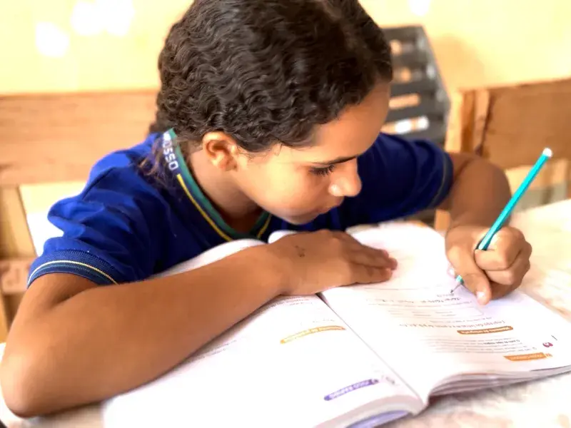 Adolescente negra fardada escrevendo em um livro