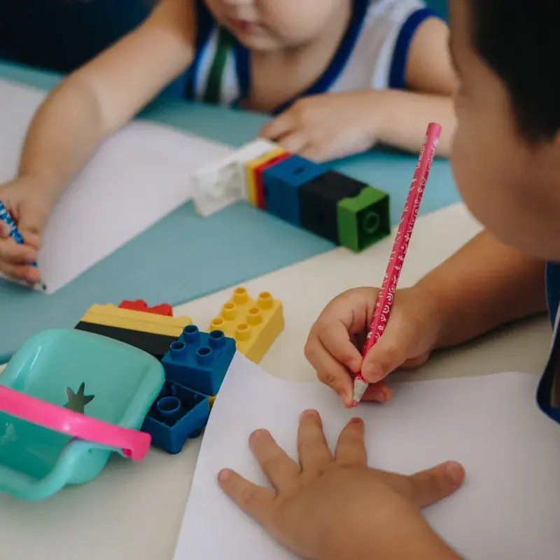 Duas crianças pequenas com lápis e papel desenhando