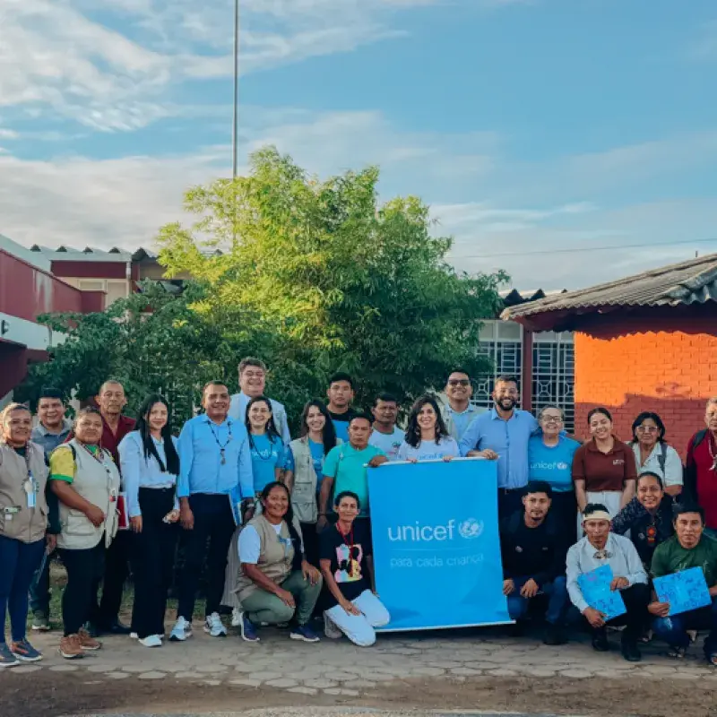 organizações indígenas e profissionais do UNICEF pousam para a foto ao ar livre com o logo do UNICEF